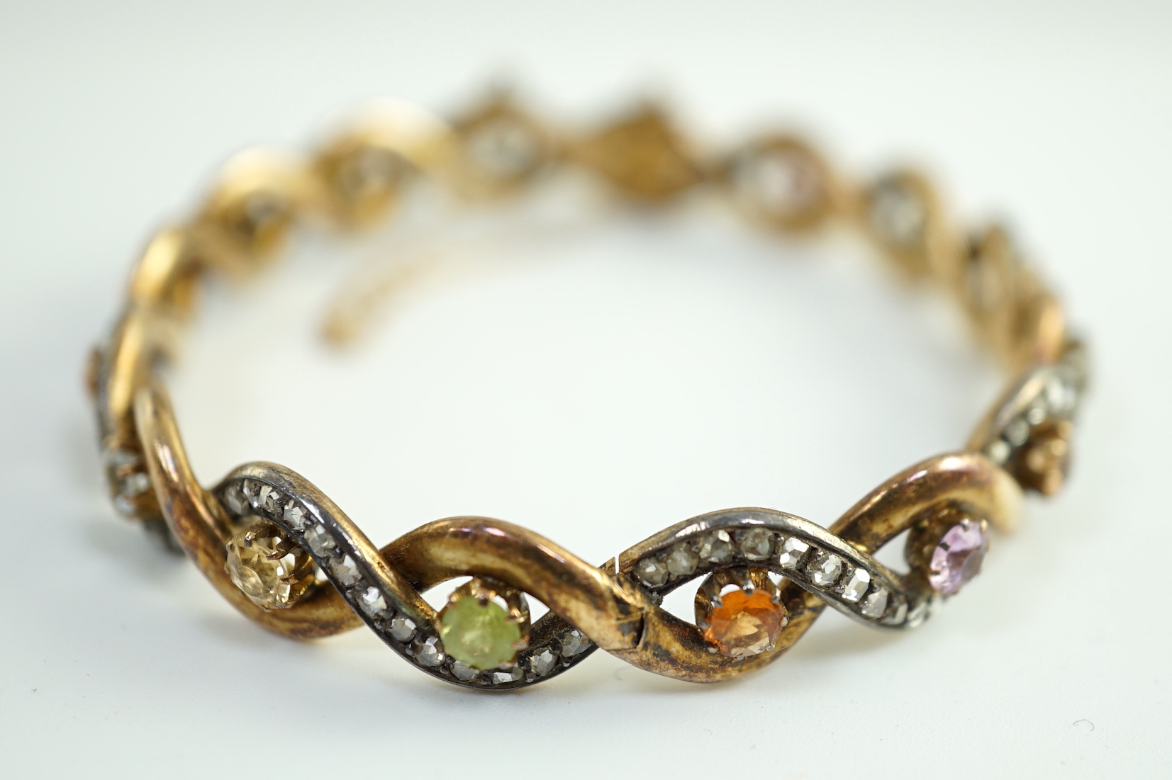 A late 19th/early 20th century French 18ct gold and silver rose cut diamond and multi gem set spiral hinged bangle